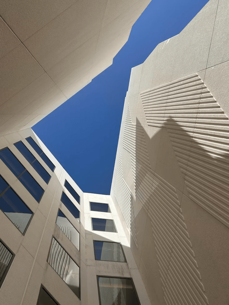 Looking up at modern architecture courtyard with bright blue sky